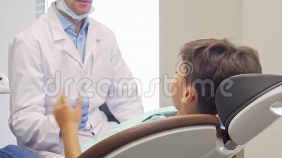 小男孩对着镜头微笑看了看镜子里健康的牙齿视频的预览图
