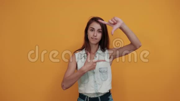 开朗的白种人年轻女人用手指做框架看上去很快乐视频的预览图