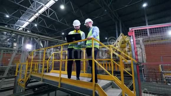 工程师在现代工业工厂用笔记本电脑工作工厂设施的专业工厂工人视频的预览图