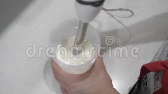 女用手将白色牛奶液与红色染料混合塑料筒搅拌机视频的预览图