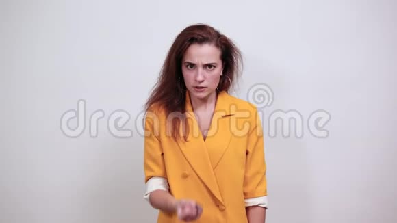 漂亮的女人穿着黄色夹克看起来很生气握着拳头威胁着视频的预览图