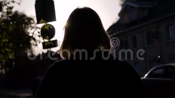 晚上的女孩绕着城市转后景你可以看到她在傍晚的阳光下的剪影太阳光线很美视频的预览图
