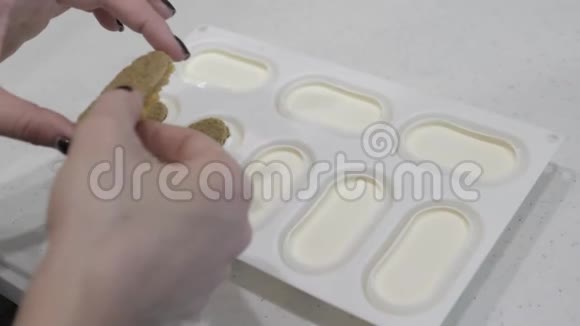 女性双手放入硅胶模具配白色奶油饼干配黄色碎屑视频的预览图