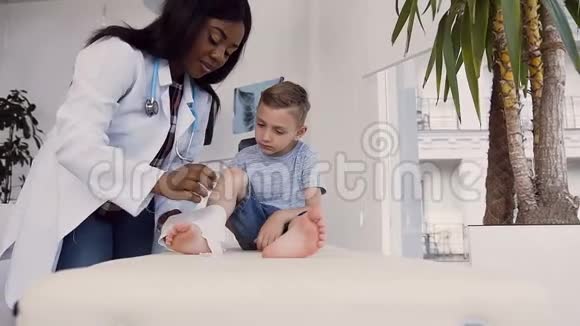 年轻的女医生从小病人的腿上取出绷带视频的预览图