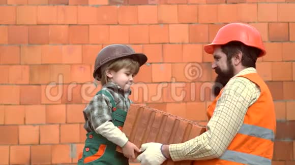 孩子和她的父母在硬帽子玩建筑块儿子帮她父亲修墙小儿子砖匠视频的预览图