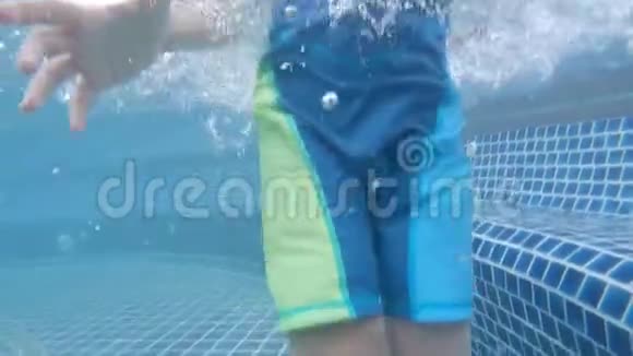 小男孩在游泳池里潜水在水下打招呼视频的预览图