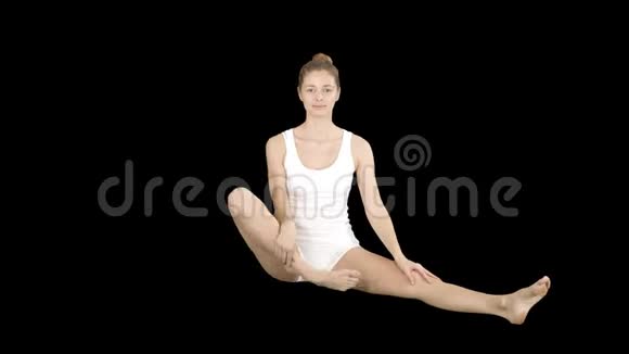 可爱的健身女性坐在莲花姿势下练习瑜伽然后微笑阿尔法频道视频的预览图
