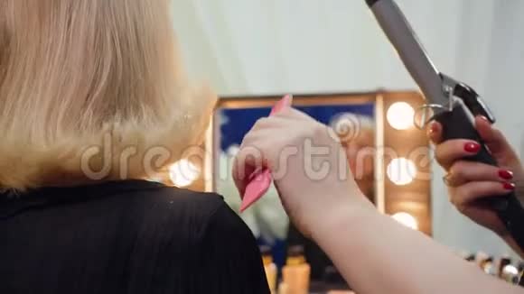 美发师正在为年长女性做发型使用卷发熨斗双手特写视频的预览图