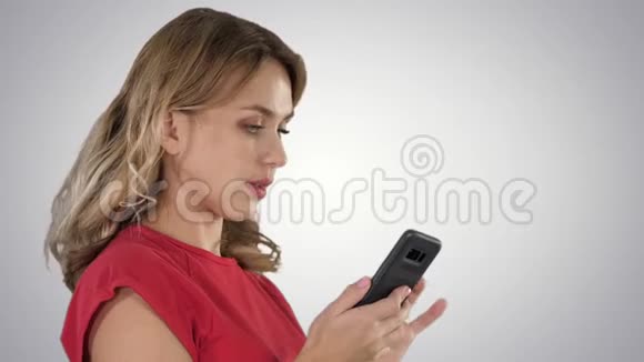 快乐的女人浏览媒体或在梯度背景下的移动智能手机上发短信视频的预览图