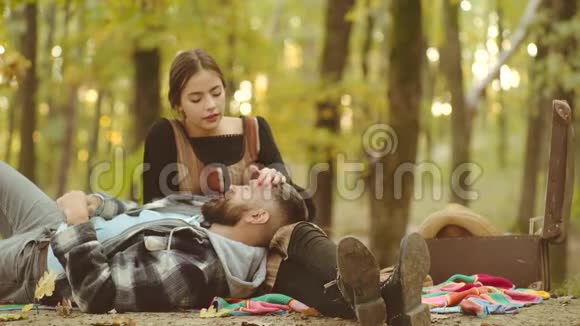 秋天的一对一对夫妇坐在公园里秋天的落叶上微笑的夫妇在秋天公园玩得很开心好好享受视频的预览图