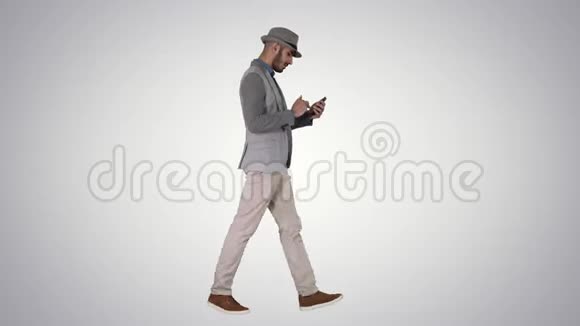 严肃的阿拉伯休闲男子使用智能手机而走在梯度背景视频的预览图