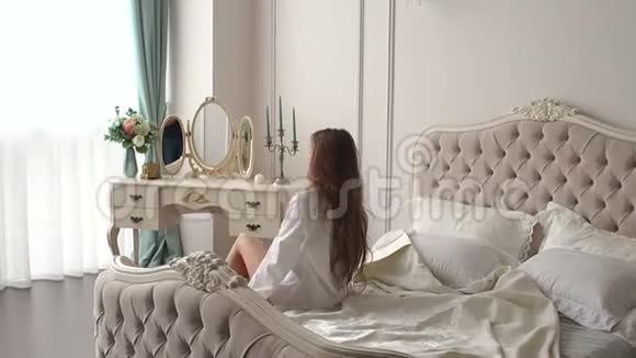 一个留着长发的女人醒来在卧室里伸展身体慢动作视频的预览图