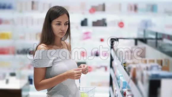 漂亮的女孩在化妆品店里选择香水喷在测试仪上慢动作视频的预览图