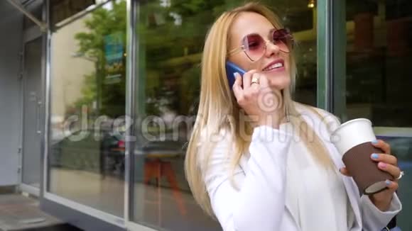 微笑的金发已婚女人在城市大街上用手机聊天视频的预览图