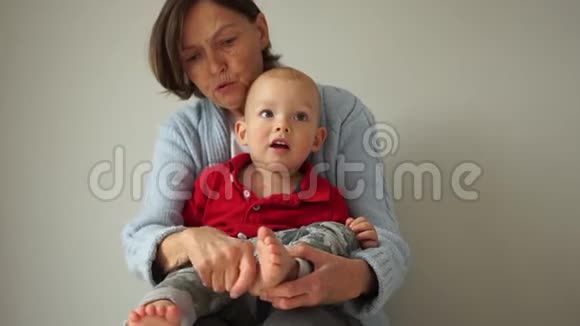 一位快乐的祖母和她年轻的孙子的肖像女人把孩子抱在怀里挠痒痒视频的预览图
