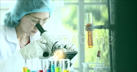 惊慌美丽的亚洲科学家为她在实验室的实验调整显微镜视频的预览图