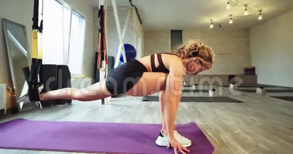 有吸引力的运动女士伸展集中她的腿使用带子TRX锻炼有困难的锻炼以获得更多的健康视频的预览图