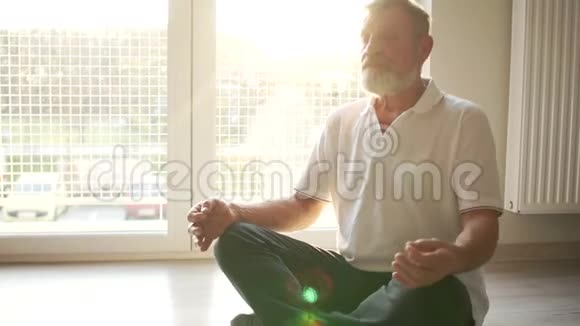 瑜伽课程修行一位年长的瑜伽士坐在地板上的莲花位置阳光照射视频的预览图