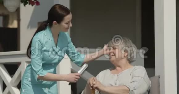 红网拍摄的阳光明媚的日子看护人员正在给养老院照顾老人的老太太梳头视频的预览图