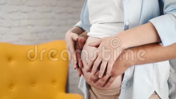 亲密的母亲和父亲用手抚摸裸露的大肚子有积极的情绪视频的预览图