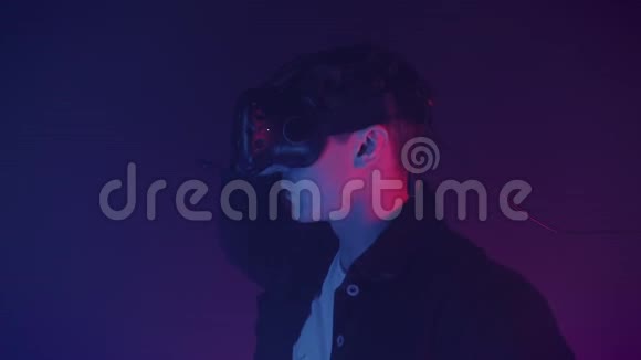 年轻迷人的男人移除虚拟现实耳机和看镜头的肖像数码照明背景视频的预览图