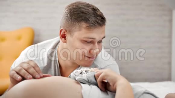 男性未来父母用童鞋触摸裸露怀孕女性腹部的特写脸视频的预览图