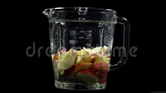 苹果落在搅拌机里有水混合制成家庭果汁慢运动黑色背景视频的预览图