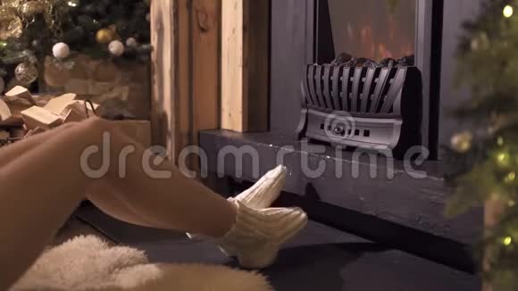 女人在温暖的火中穿着羊毛袜和喝一杯热茶放松视频的预览图