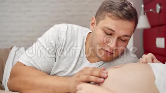 亲密的年轻父亲有积极的情绪抚摸着怀孕的大肚子享受着亲子关系视频的预览图