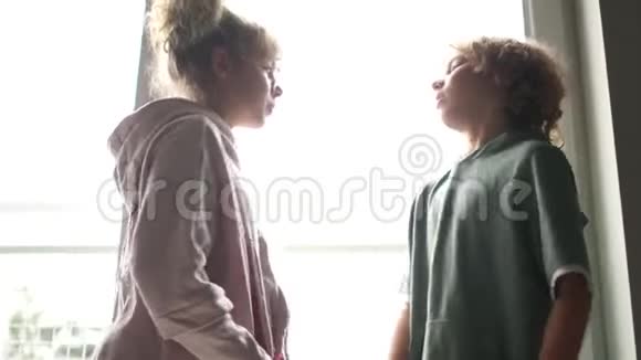 男孩和女孩站在窗户前的室内孩子们互相欺负吵架视频的预览图