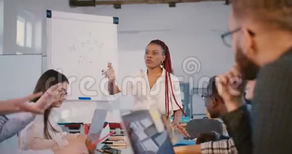 年轻的职业积极的黑人商业导师妇女在现代时尚办公室研讨会上给合作伙伴指示视频的预览图
