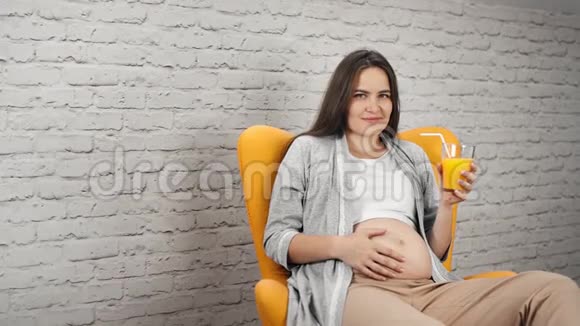 年轻怀孕少女用清爽的维他命橙汁触摸赤裸的腹部视频的预览图