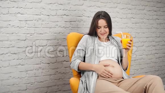 幸福的孕妇裸着大肚子抚摸着鲜橙汁中弹视频的预览图