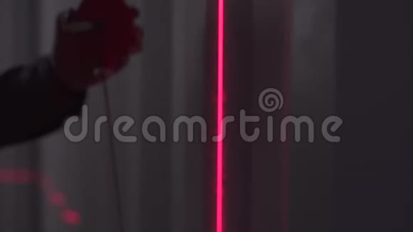 男人的剪影在黑暗中用条形码扫描仪的红线把厚厚的线夹在墙上库存录像关闭视频的预览图