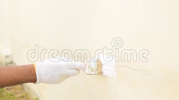 用白色布手套把手合起来用它来改变油漆来密封混凝土墙上的裂缝视频的预览图