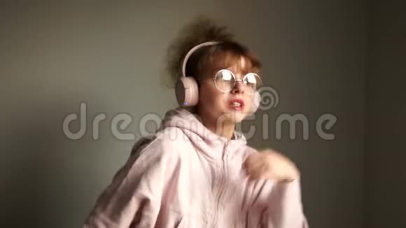 可爱的十几岁女孩戴着眼镜卷发用无线耳机听音乐蓝牙技术视频的预览图