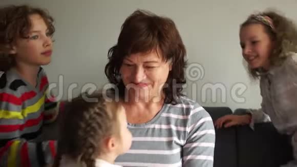 祖母和孙辈摆姿势两个女孩和一个男孩快乐的孩子们拥抱他们的祖母室内画像视频的预览图