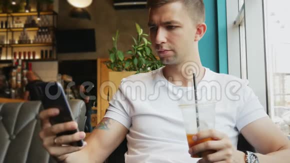 年轻的商人在咖啡馆里用手机喝冷咖啡鸡尾酒视频的预览图