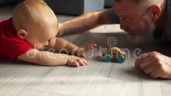 爷爷和小孙子一起玩玩具木车照顾爷爷和可爱的学前孙子躺着视频的预览图
