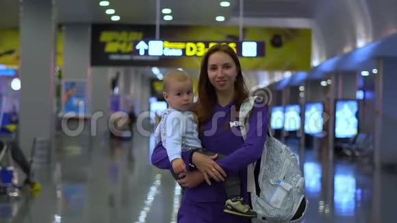 微笑的母亲带着一个美丽的婴儿在机场慢动作视频的预览图