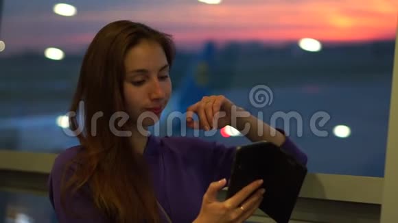 一个学生女孩用智能手机站在机场等她的航班视频的预览图