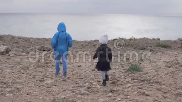 兄妹俩在海边的岩石上散步视频的预览图