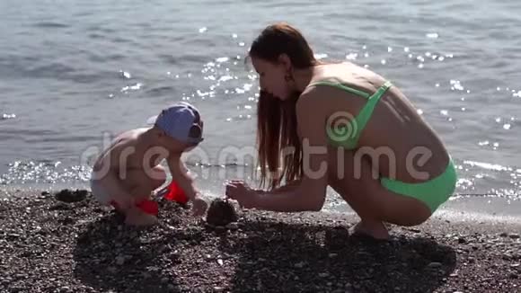 妈妈和宝宝正在海边缓慢地建造沙滩上的沙像视频的预览图