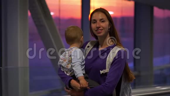 漂亮的女孩手牵手小儿子在机场靠近窗户慢动作视频的预览图