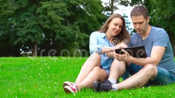 男人和女人在公园里用平板电脑视频的预览图