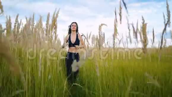 适合女人慢跑锻炼跑步的心脏户外通过高大的草地在夏季的田野女跑步运动员视频的预览图