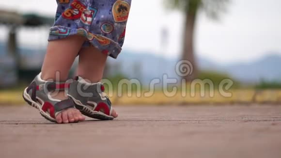 一个小男孩穿着凉鞋慢悠悠地走在路上的腿视频的预览图