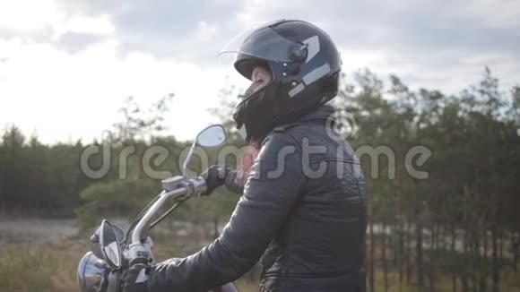 自信的女孩戴着黑色头盔坐在摩托车上回头看路爱好旅游和活动视频的预览图