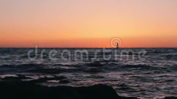 令人难以置信的橙色日落小帆船在地平线上日落时漂浮在海上的小帆船剪影赛的剪影视频的预览图