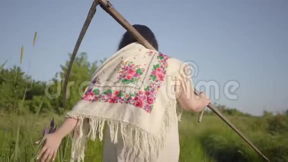 穿着传统披肩的超重女性在辛苦工作后的夏季野外行走的背影视频的预览图